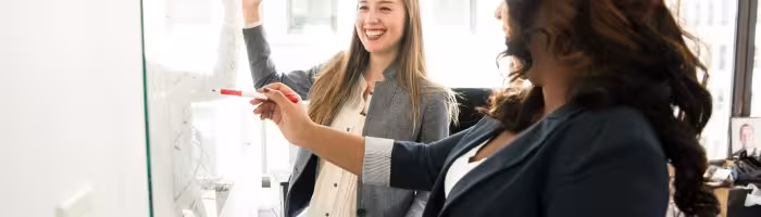 Zwei Frauen stehen an einem Whiteboard